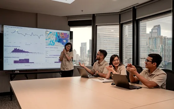 Tim berdiskusi di ruang rapat dengan grafik data tampil di layar besar