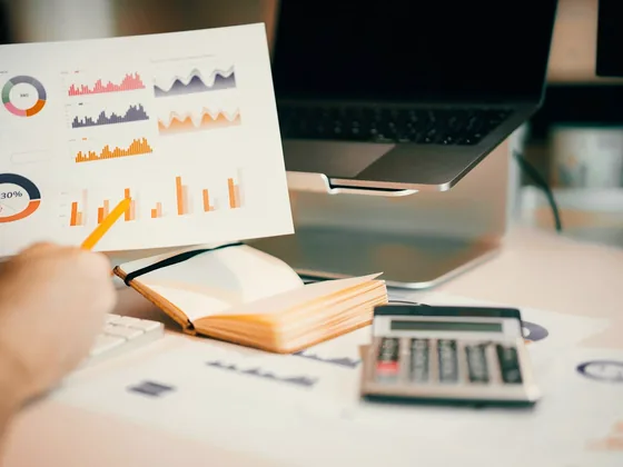 Tangan menata lembar grafik penjualan di atas meja kerja